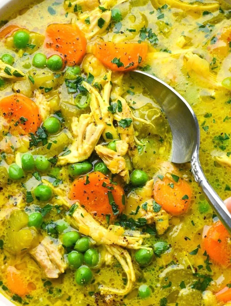 Bowl of anti-inflammatory turmeric chicken soup garnished with herbs.