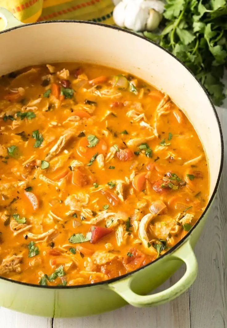 Bowl of chicken tortilla soup garnished with tortilla strips and avocado