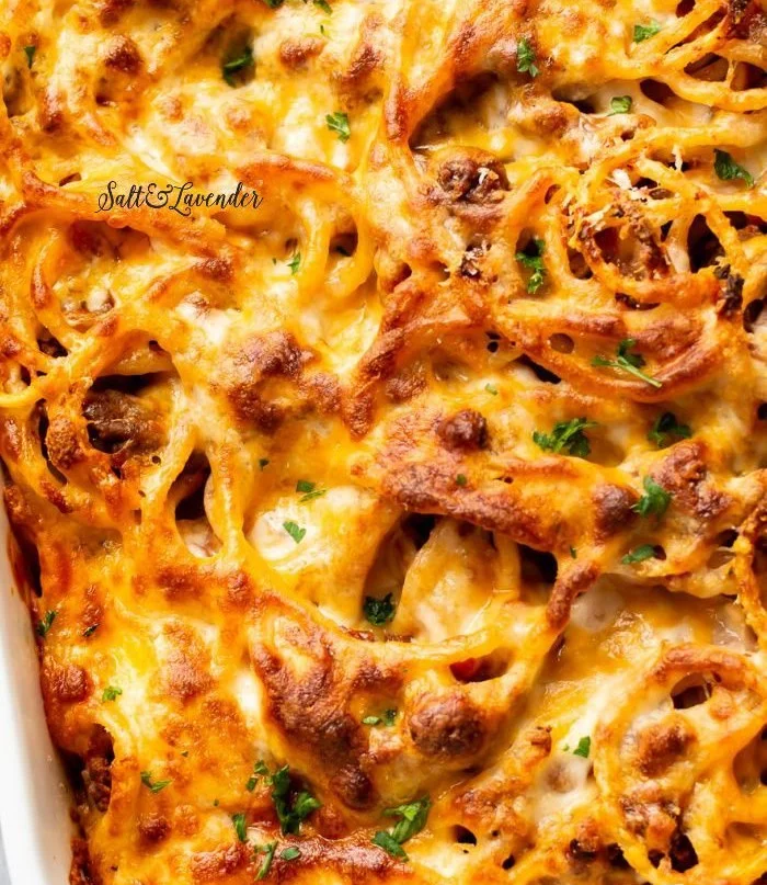 Delicious cheesy baked spaghetti served in a dish with melted cheese on top.