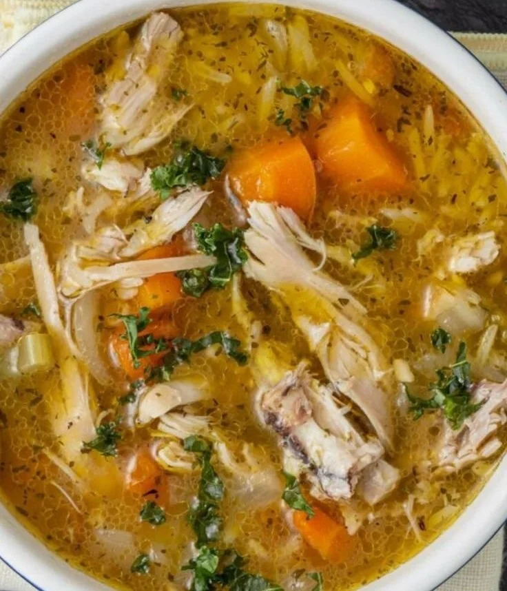 Bowl of chicken rice soup with vegetables and herbs
