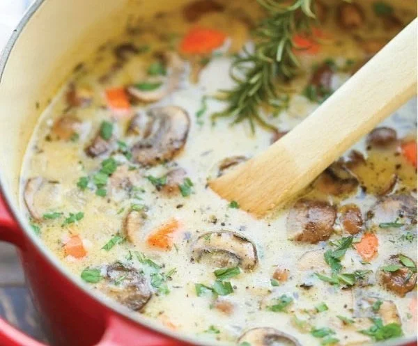 Bowl of creamy chicken and mushroom soup garnished with herbs
