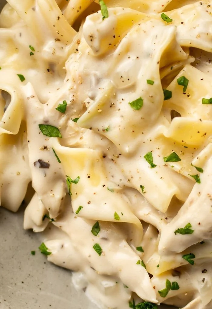 Creamy chicken and noodles served in a bowl with fresh herbs and spices
