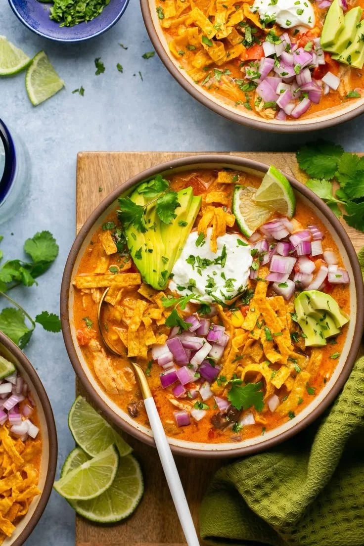 Bowl of creamy high protein chicken enchilada soup topped with cheese and cilantro