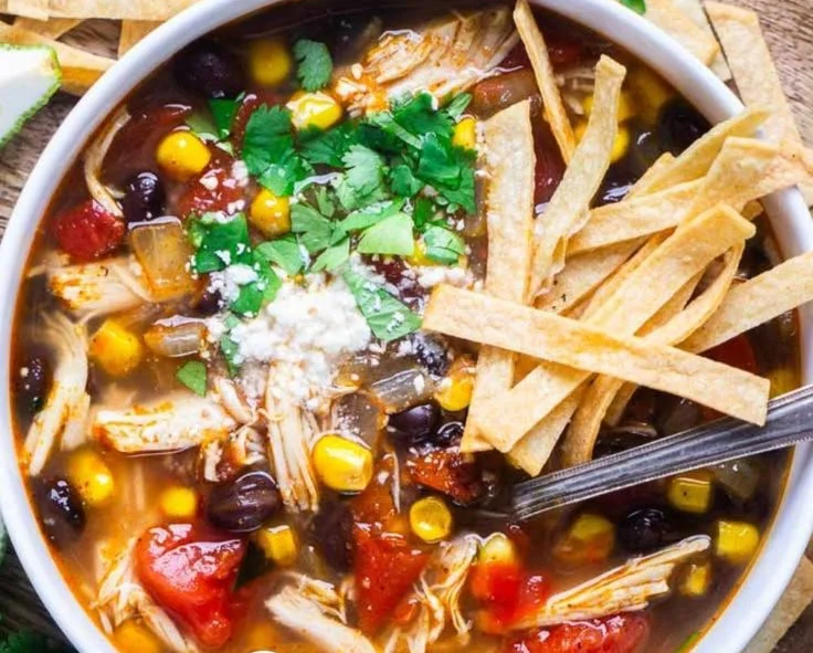 Bowl of easy tortilla soup garnished with crispy tortilla strips and avocado