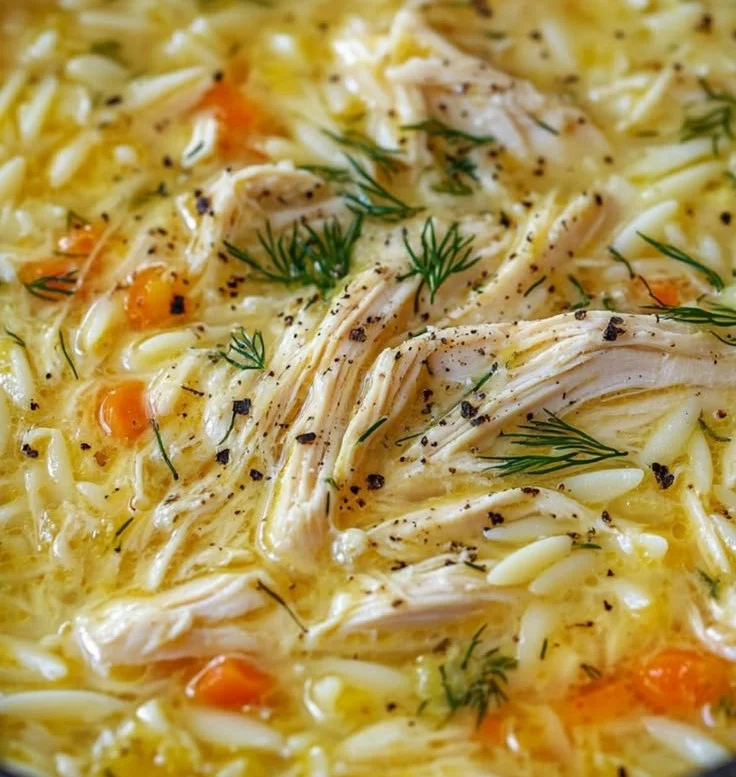 Bowl of Greek Lemon Chicken Soup garnished with fresh herbs and lemon slices.