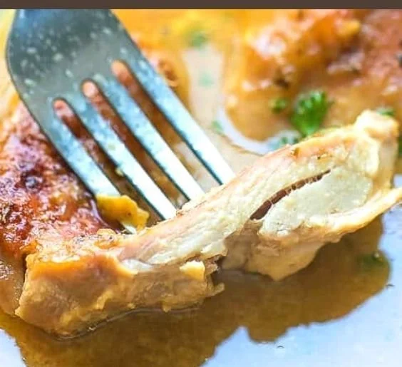 Juicy honey mustard chicken thighs garnished with herbs on a white plate.