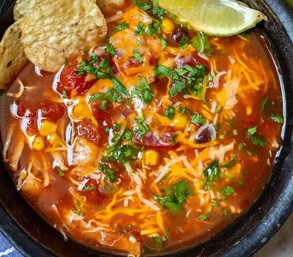 Bowl of Instant Pot Chicken Tortilla Soup topped with tortilla strips and cilantro