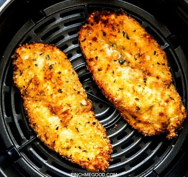 Delicious air fryer fried chicken served on a plate with herbs.