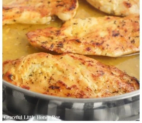 Oven-baked honey mustard chicken with herbs and spices on a plate.