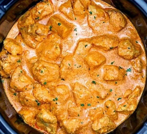 Delicious slow cooker butter chicken served with rice and garnish.