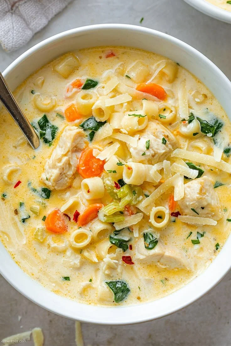 Creamy chicken pasta soup with cheese in a bowl, garnished and ready to serve