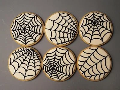A variety of decorated Halloween cookies in spooky shapes and colors.