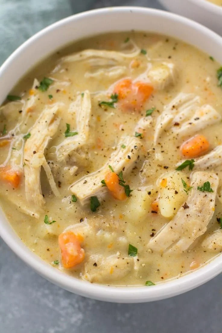 Bowl of healthy chicken pot pie soup with vegetables and herbs