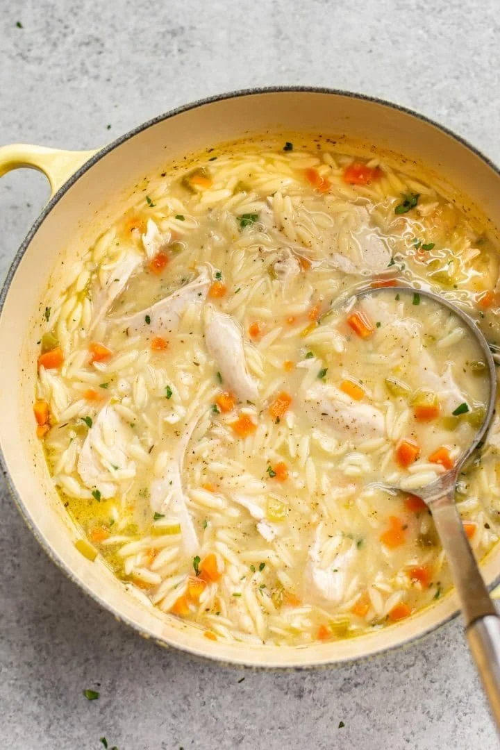 Bowl of Lemon Chicken Orzo Soup garnished with herbs and lemon slices